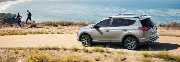 The 2018 Toyota RAV4 driving down a road by the beach and ocean.